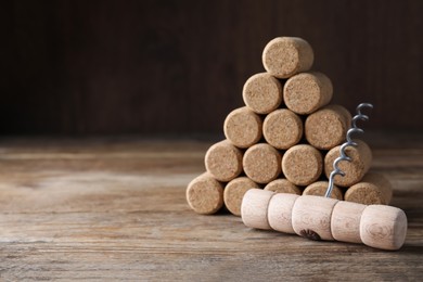 Photo of Corkscrew and wine corks on wooden table. Space for text