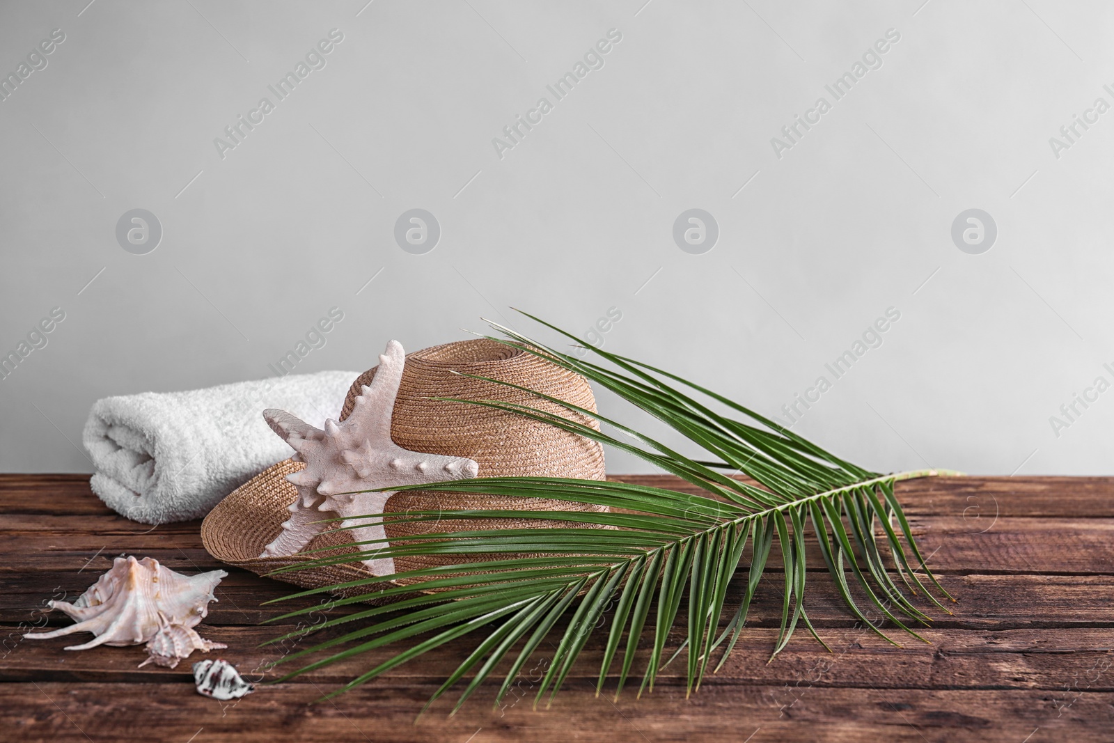 Photo of Beach objects and palm leaf on wooden table against color background