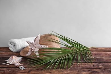 Beach objects and palm leaf on wooden table against color background