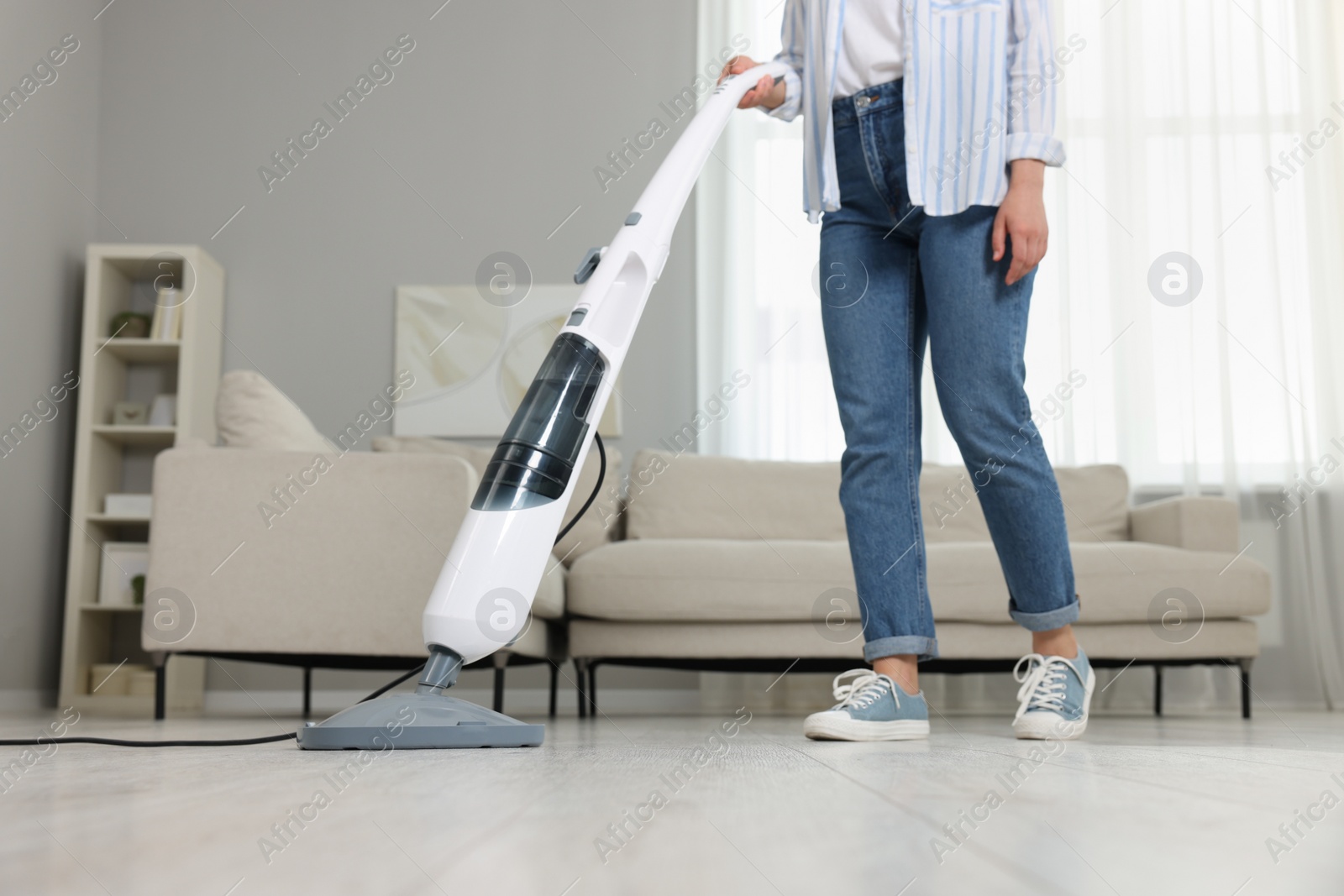 Photo of Woman cleaning floor with steam mop at home, closeup