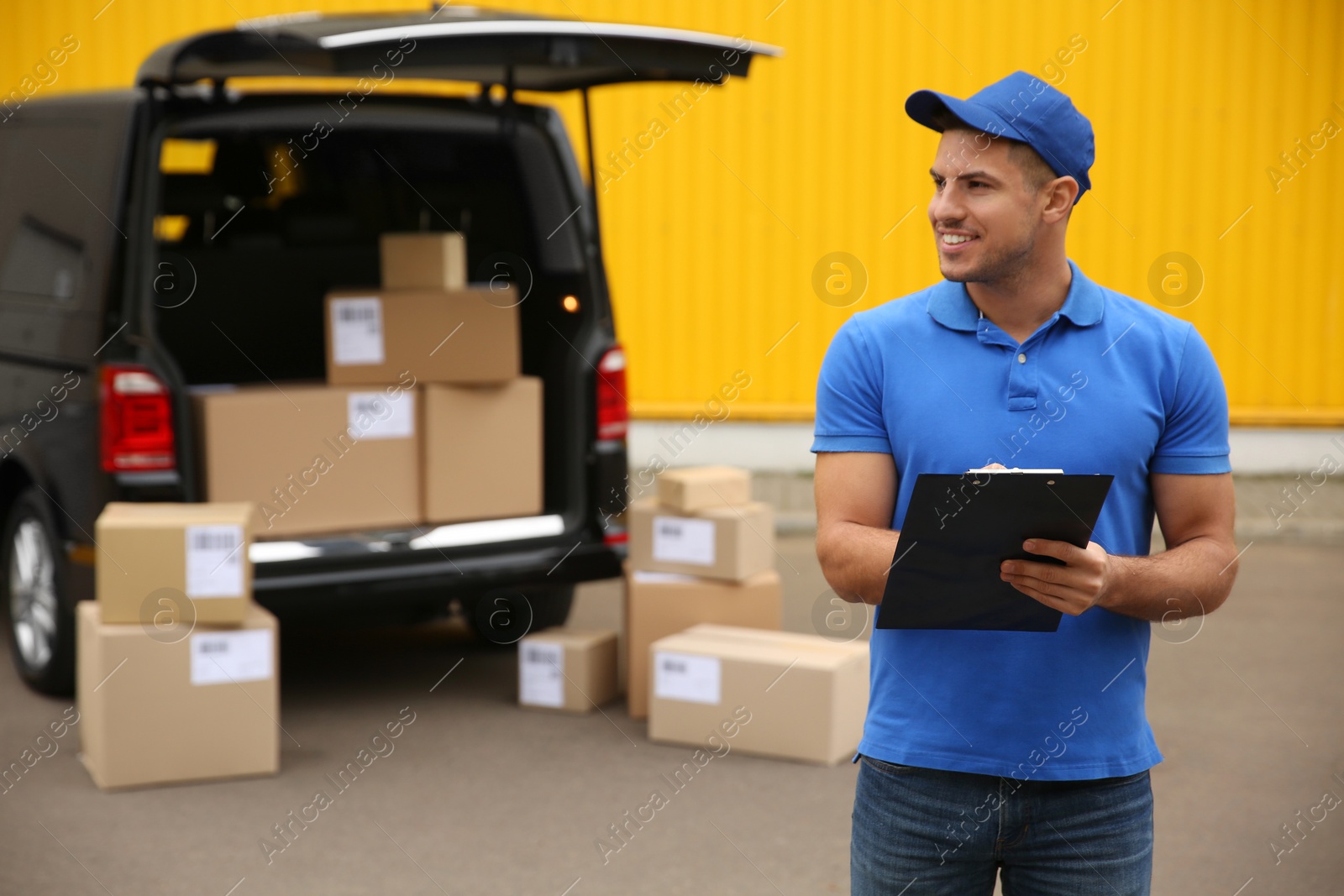 Photo of Courier with clipboard near delivery van outdoors