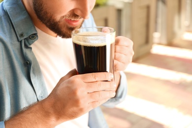 Young man with cold kvass outdoors, closeup. Traditional Russian summer drink