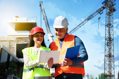 Image of Professional engineer and foreman in safety equipment with tablet at construction site