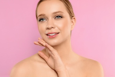 Portrait of young woman with beautiful face on pink background, closeup