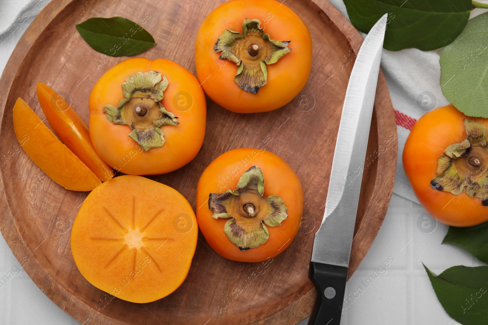 Photo of Delicious ripe persimmons and knife on white table, flat lay