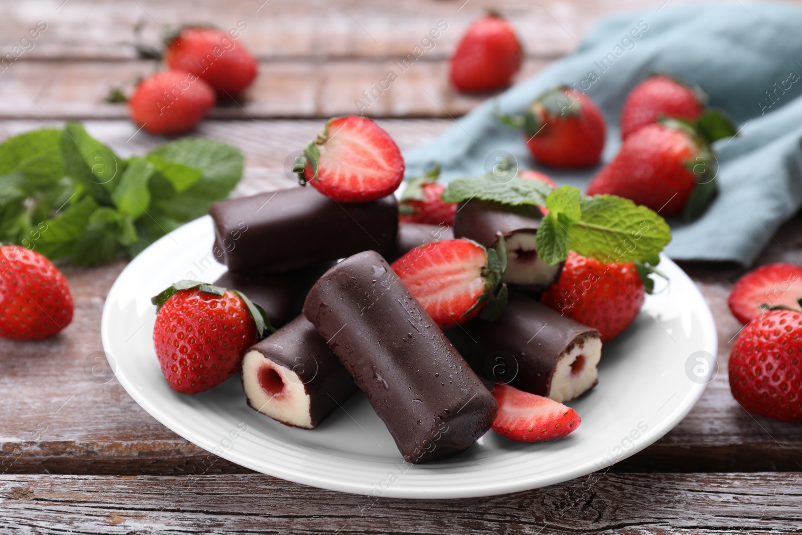 Photo of Delicious glazed curd snacks with fresh strawberries and mint on wooden table