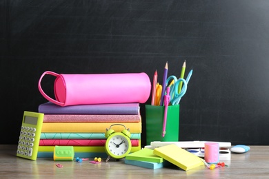 Photo of Different school stationery on table near chalkboard