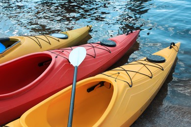 Photo of Modern kayaks with paddle on beach near river. Summer camp activity