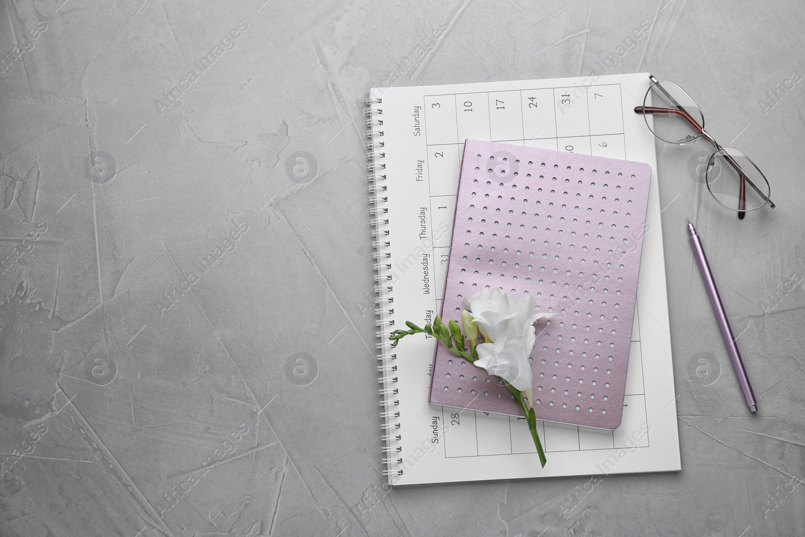 Photo of Flat lay composition with calendar, notebook and beautiful flower on grey table. Space for text