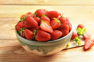 Photo of Bowl with fresh ripe strawberries on wooden table