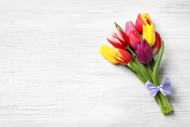 Beautiful spring tulips on white wooden table, top view. Space for text