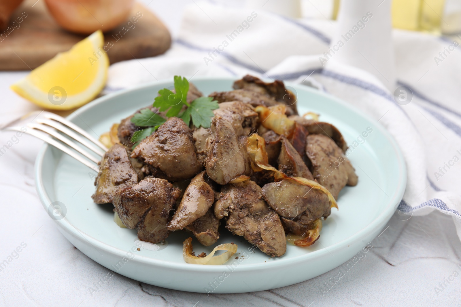 Photo of Tasty fried chicken liver with onion and fork on white textured table