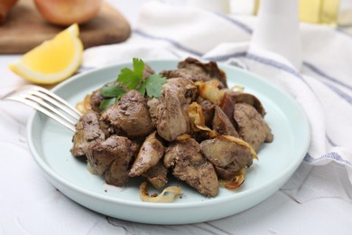 Tasty fried chicken liver with onion and fork on white textured table