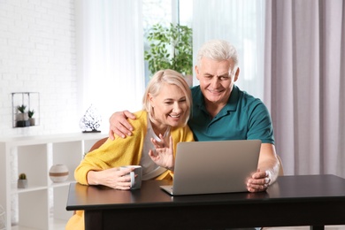 Mature couple using video chat on laptop at home