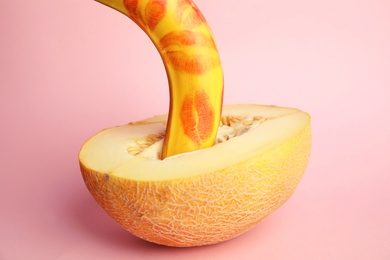Photo of Fresh banana with red lipstick marks and melon on pink background. Sex concept