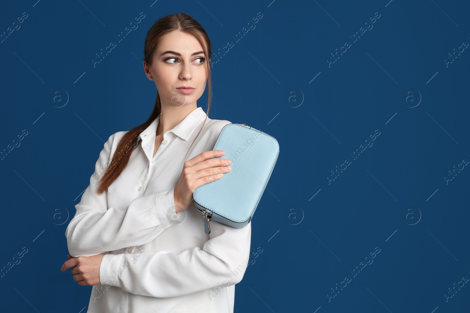 Photo of Beautiful young woman with stylish bag on blue background. Space for text