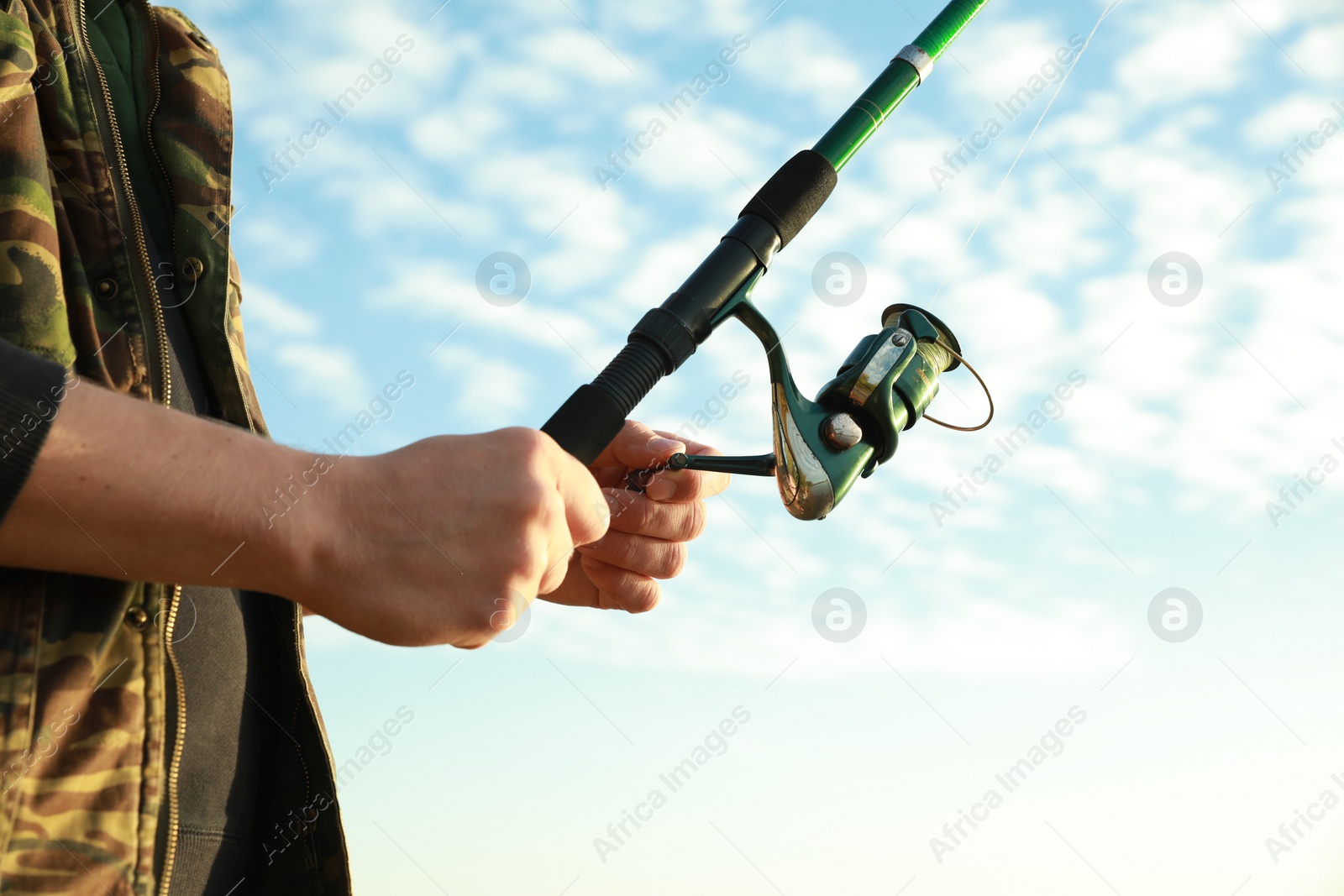 Photo of Fisherman with rod fishing under blue sky, closeup