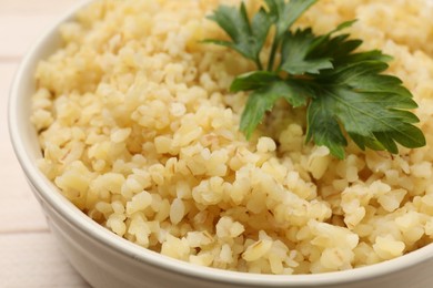 Photo of Delicious bulgur with parsley in bowl, closeup