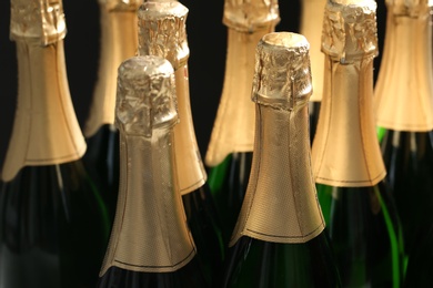 Photo of Many bottles of champagne on dark background, closeup