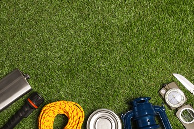 Photo of Set of traveler's equipment on green grass, flat lay. Space for text