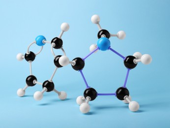 Photo of Molecule of nicotine on light blue background. Chemical model