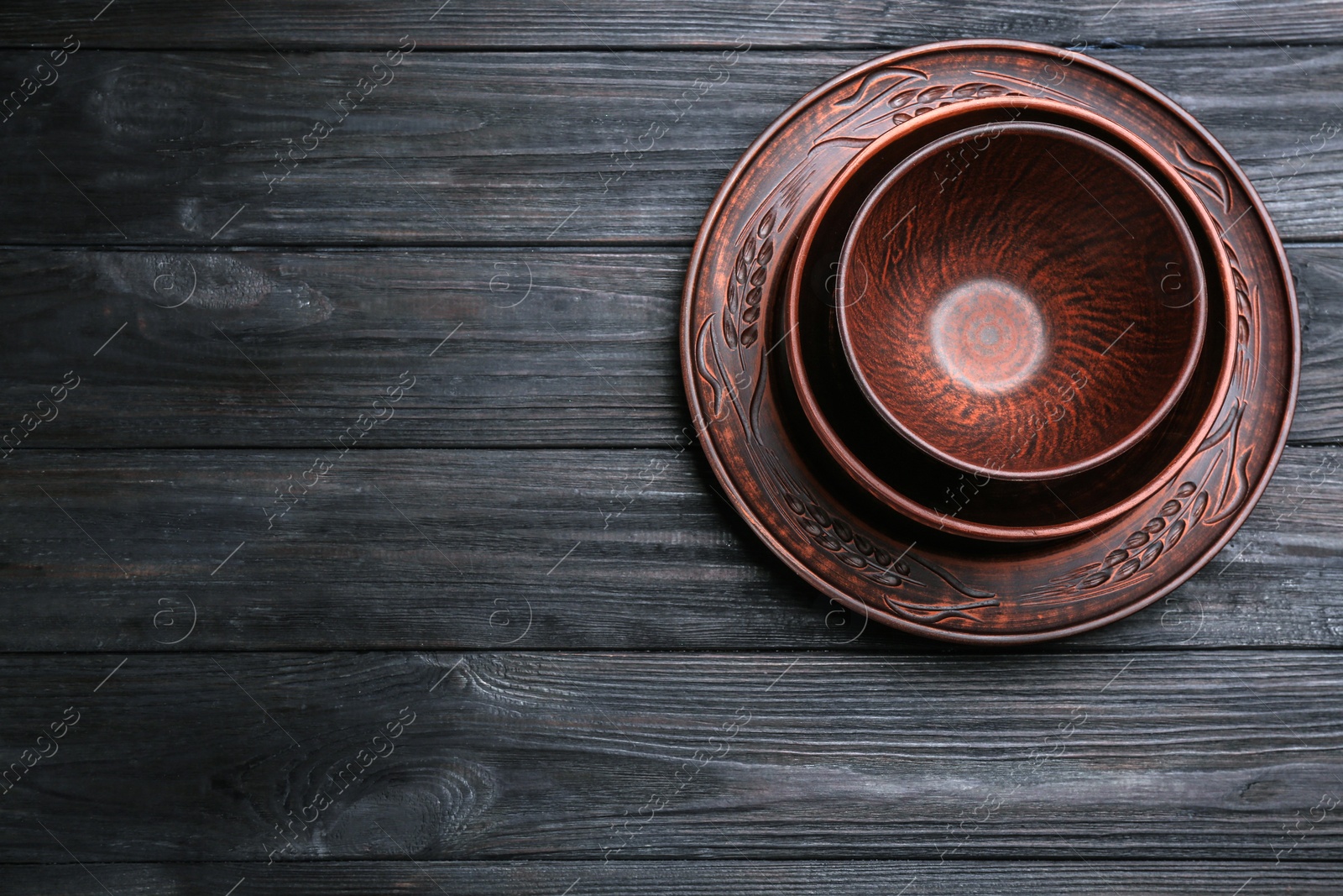 Photo of Set of clay utensils on black wooden table, top view. Space for text