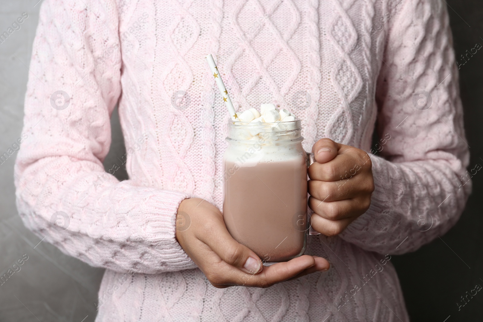 Photo of Woman holding mason jar of delicious cocoa drink with marshmallows, closeup