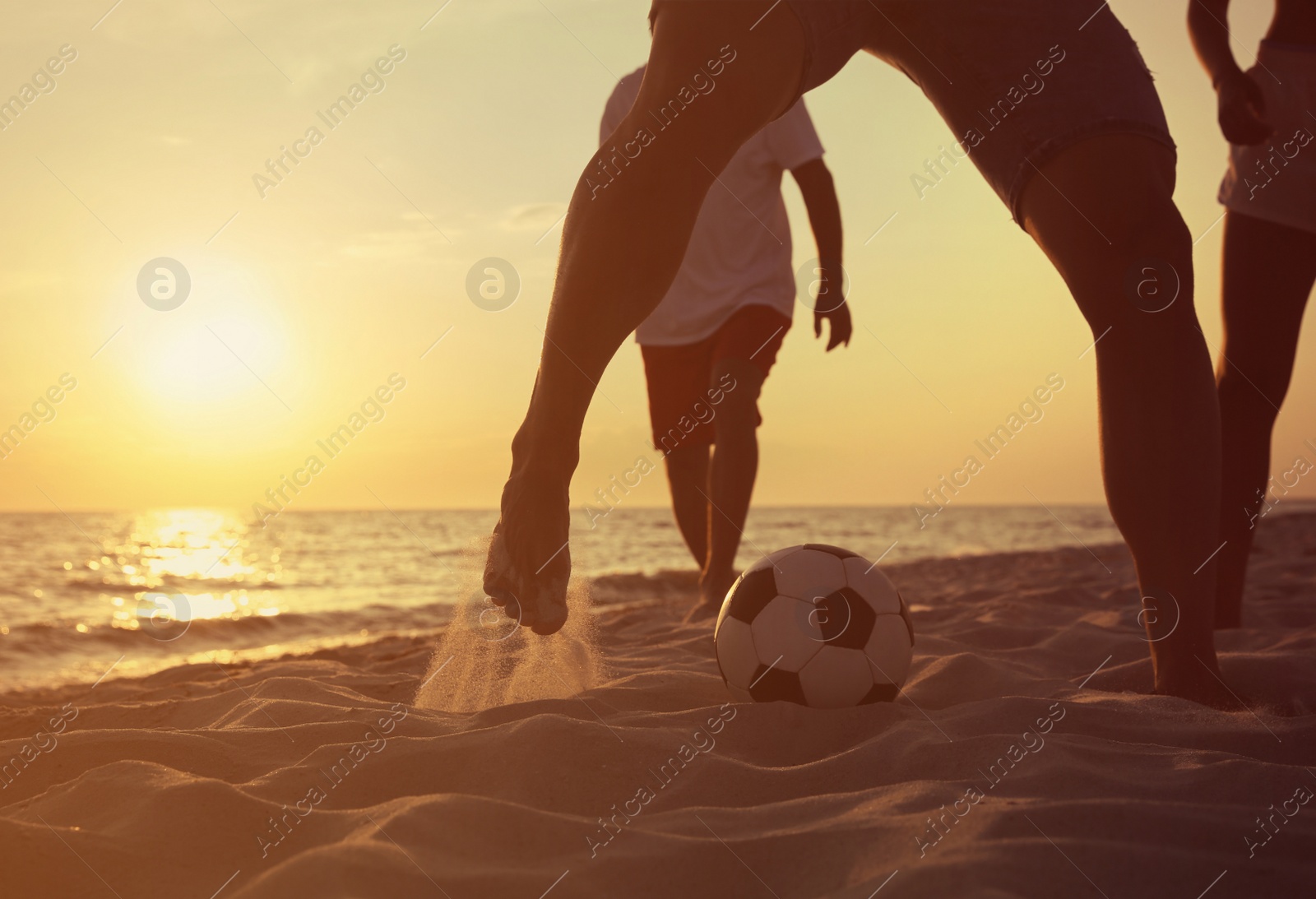 Photo of Friends playing football on beach at sunset, closeup