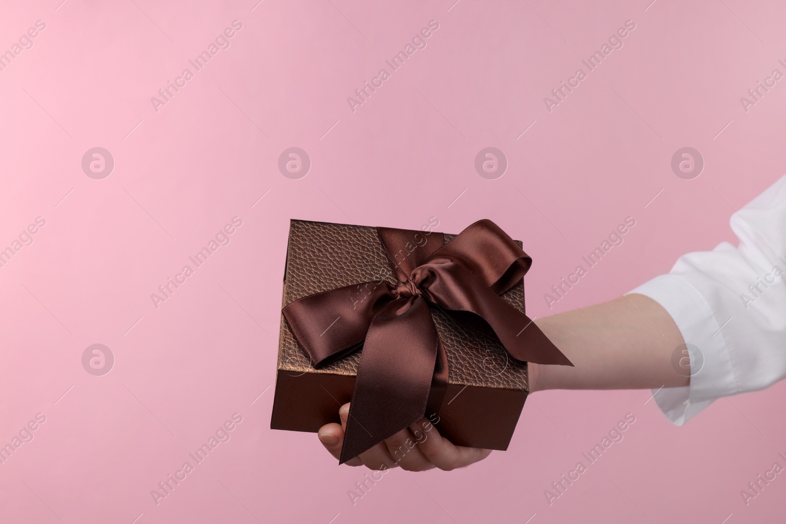 Photo of Doctor holding gift box on pink background, closeup. Medical present