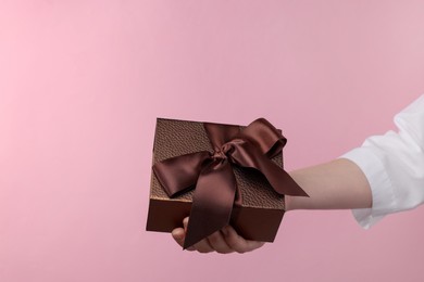 Doctor holding gift box on pink background, closeup. Medical present