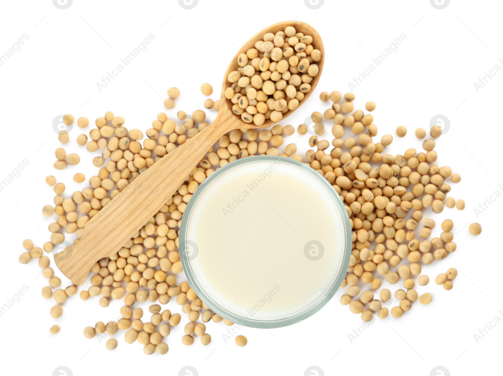 Photo of Glass of fresh soy milk and spoon with beans on white background, top view