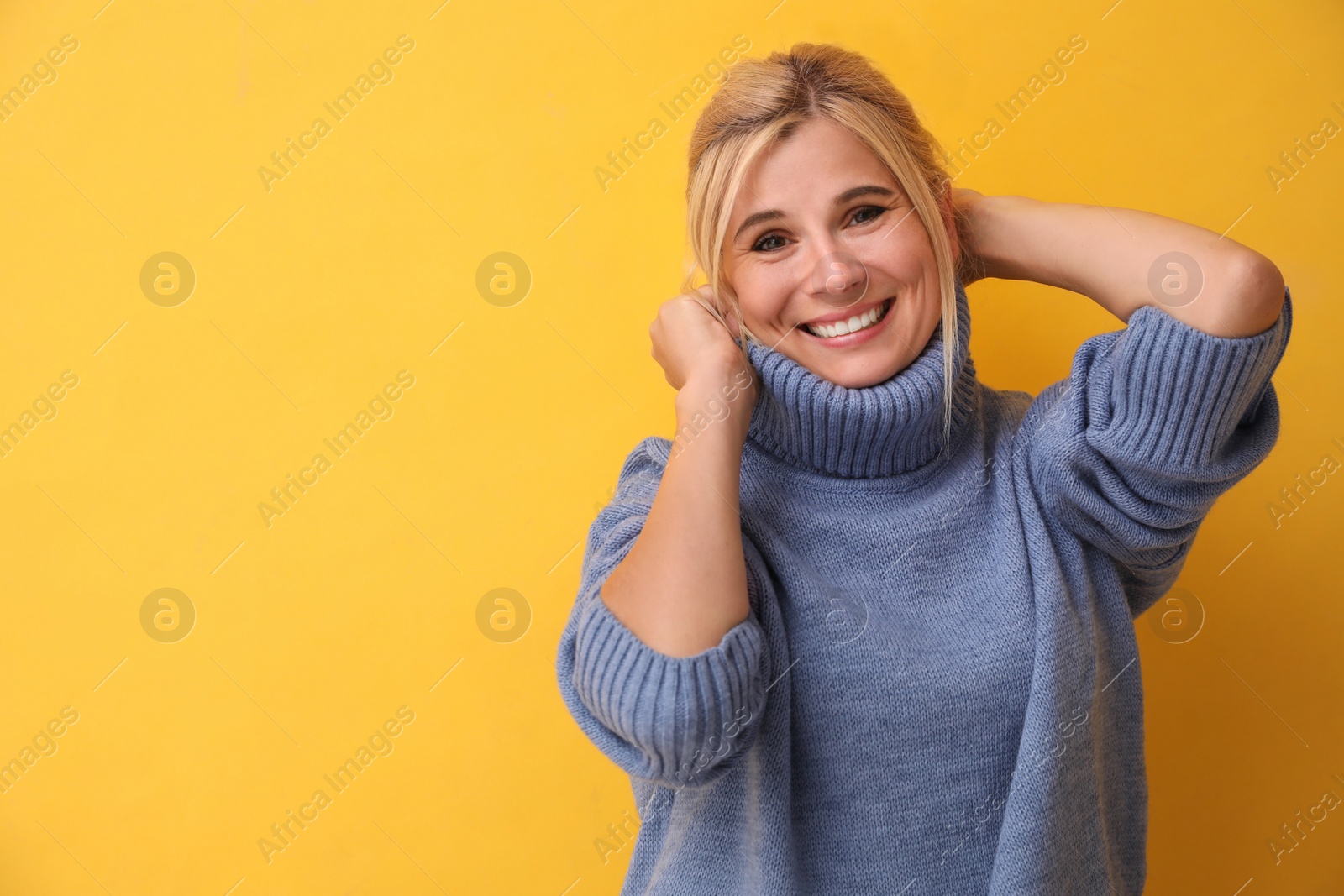 Photo of Happy woman in stylish sweater on yellow background. Space for text