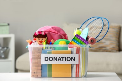 Donation box with different child toys on white table indoors