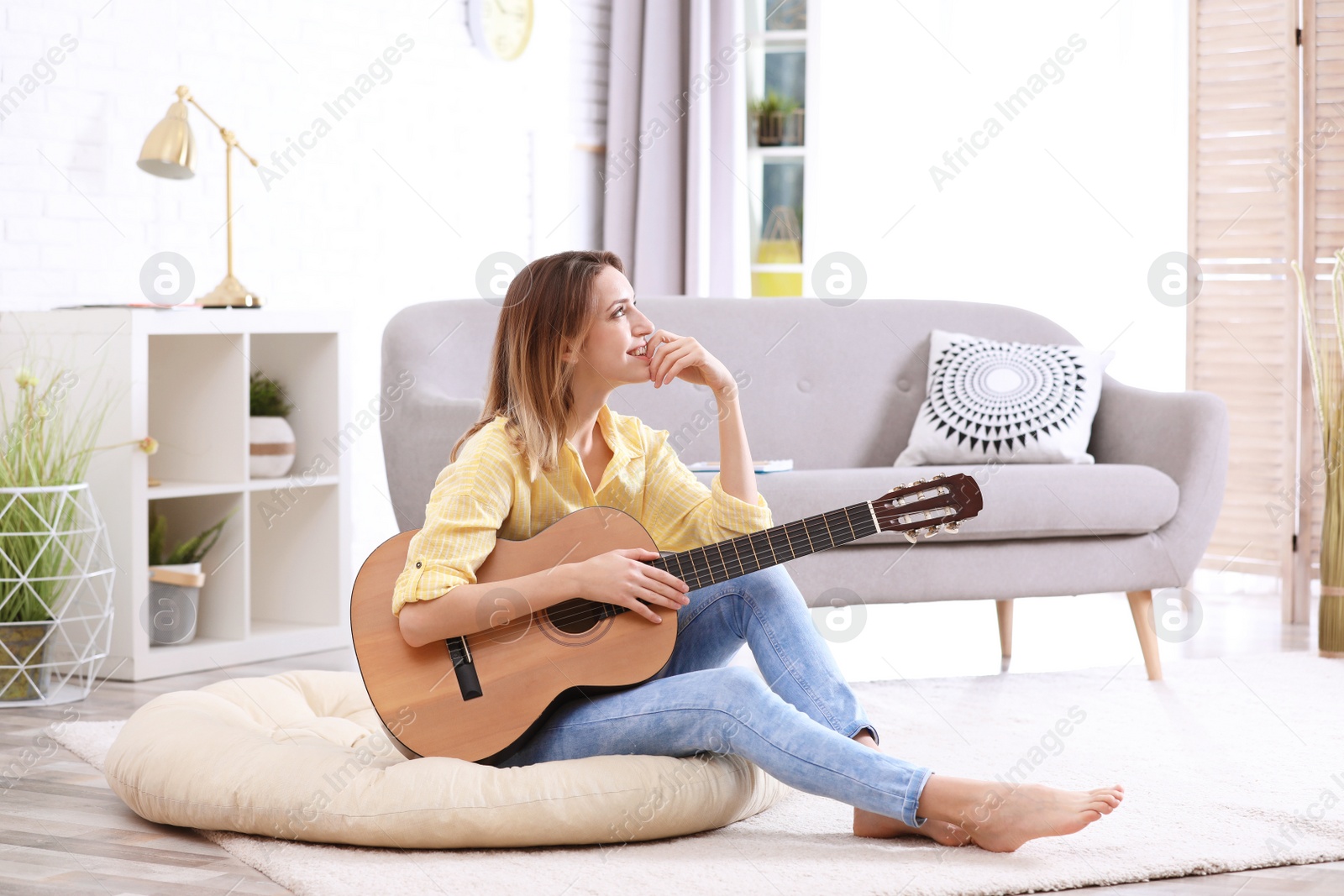 Photo of Young woman with acoustic guitar in living room