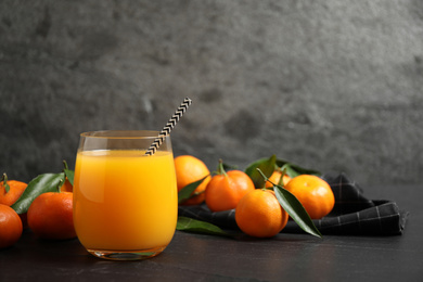 Photo of Glass of fresh tangerine juice and fruits on black table. Space for text