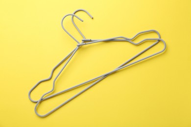 Photo of Two hangers on yellow background, top view