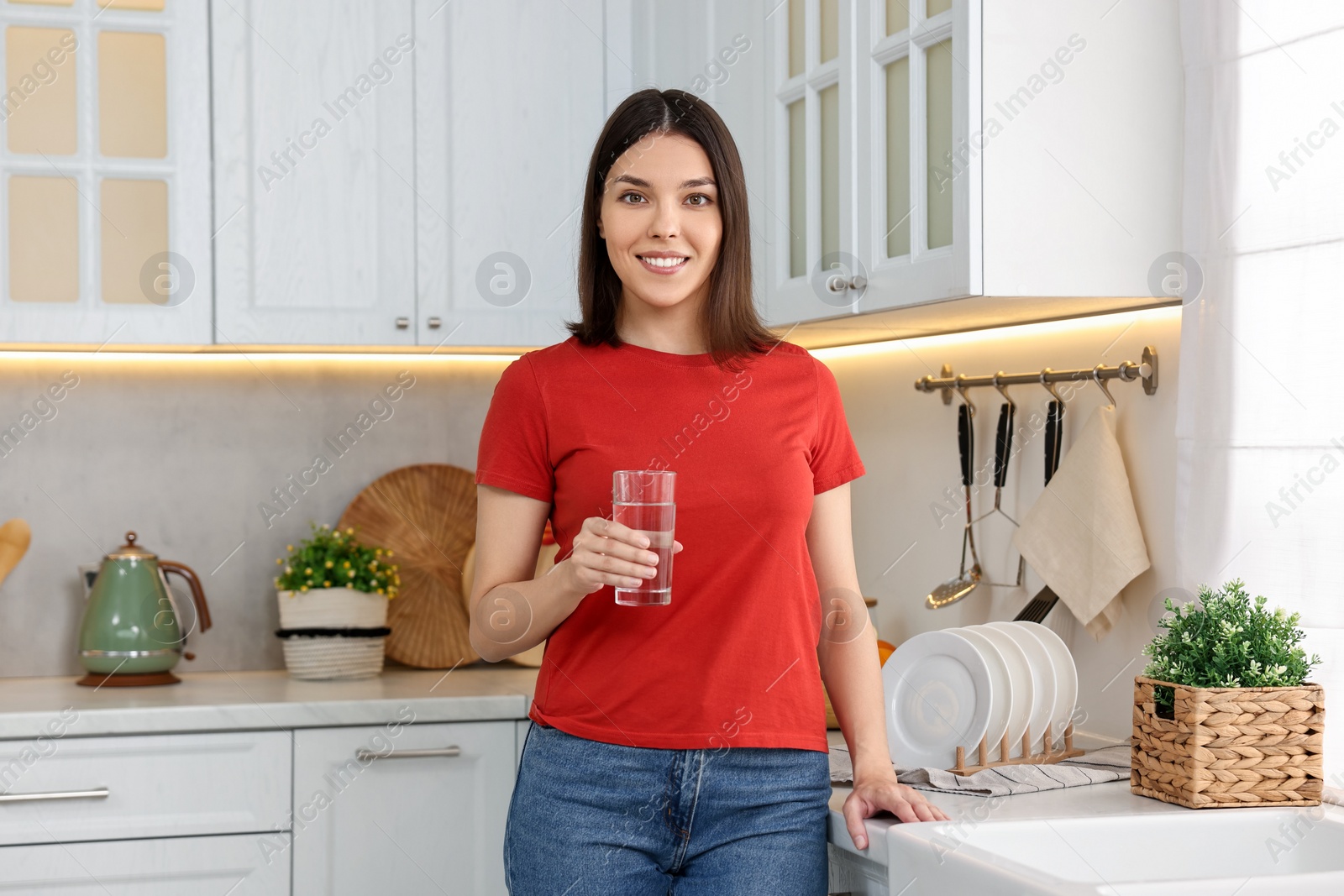 Photo of Young woman with glass of water in kitchen