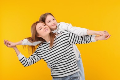 Happy mother with her cute daughter on orange background