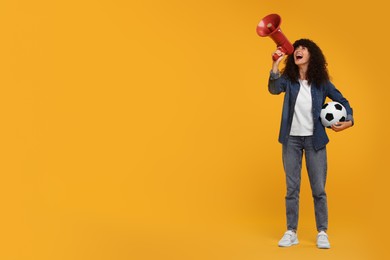 Photo of Happy fan with soccer ball using megaphone on yellow background, space for text