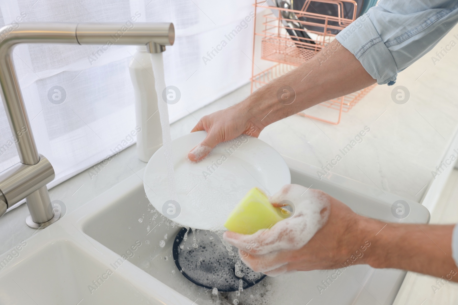 Photo of Man washing plate above sink in kitchen, closeup