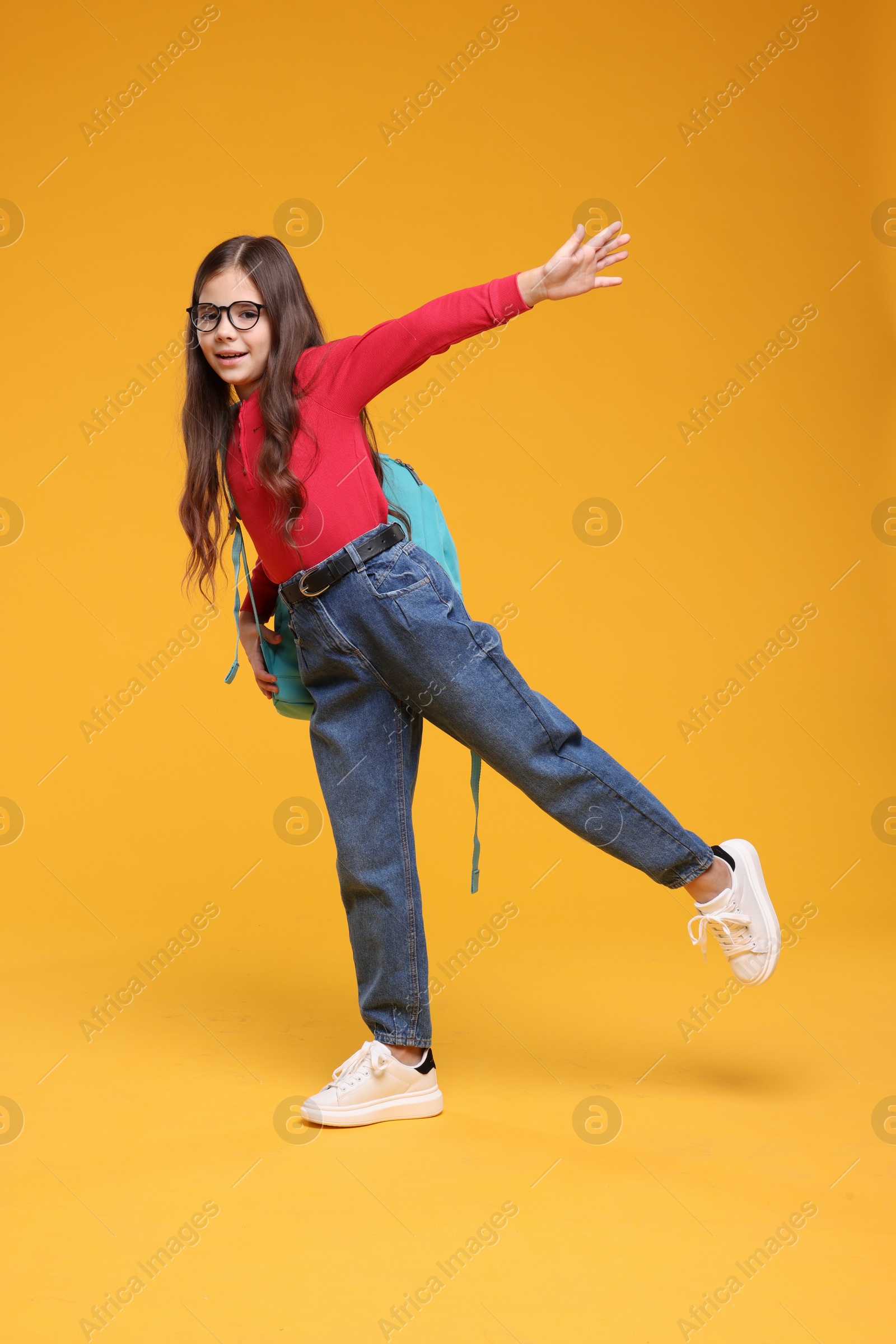 Photo of Cute schoolgirl in glasses on orange background