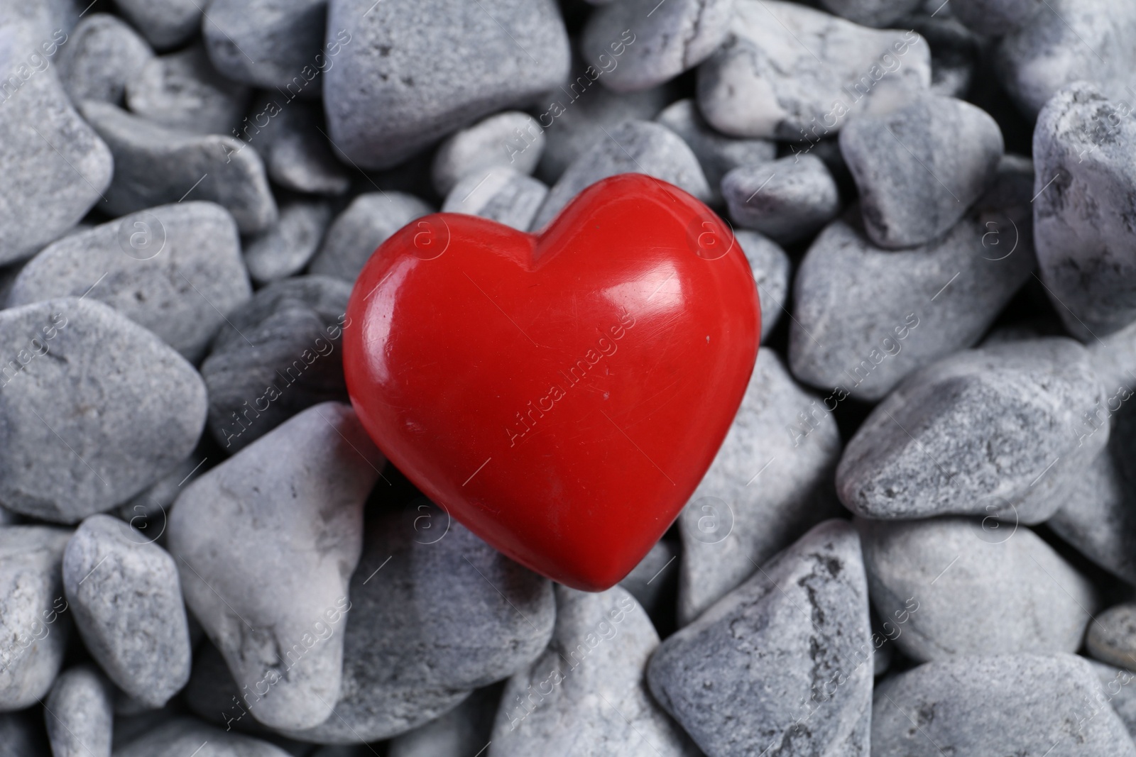 Photo of One red decorative heart on grey stones, above view