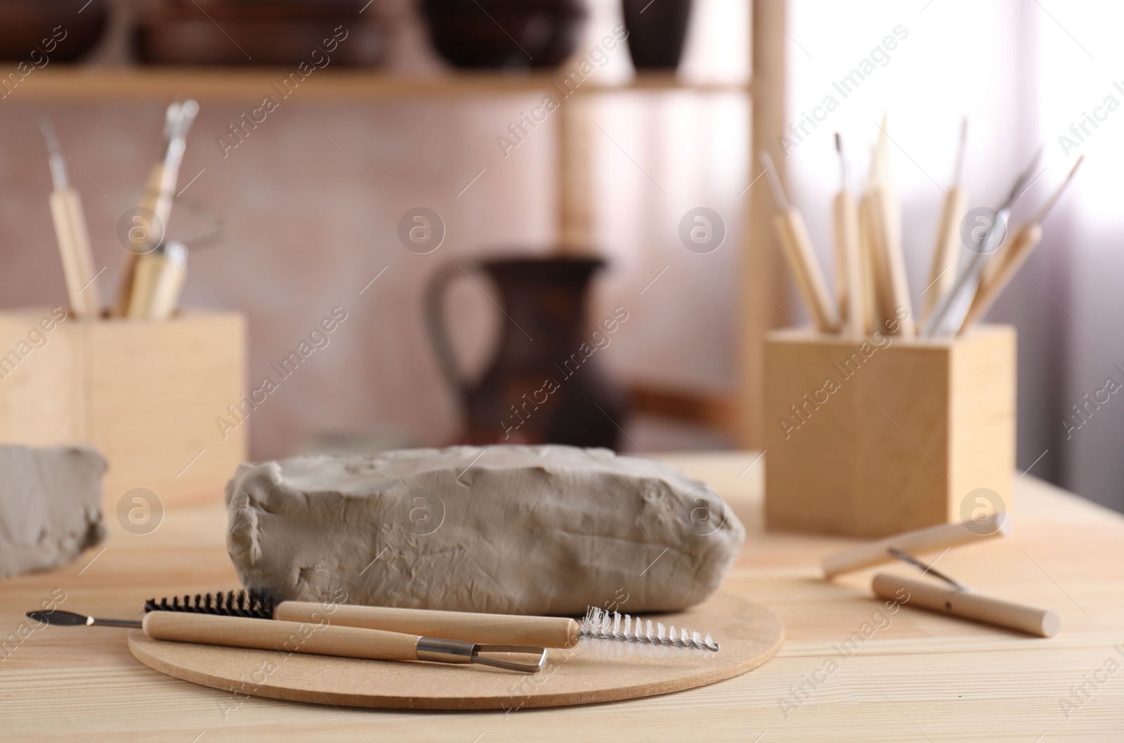 Photo of Clay and set of modeling tools on wooden table in workshop