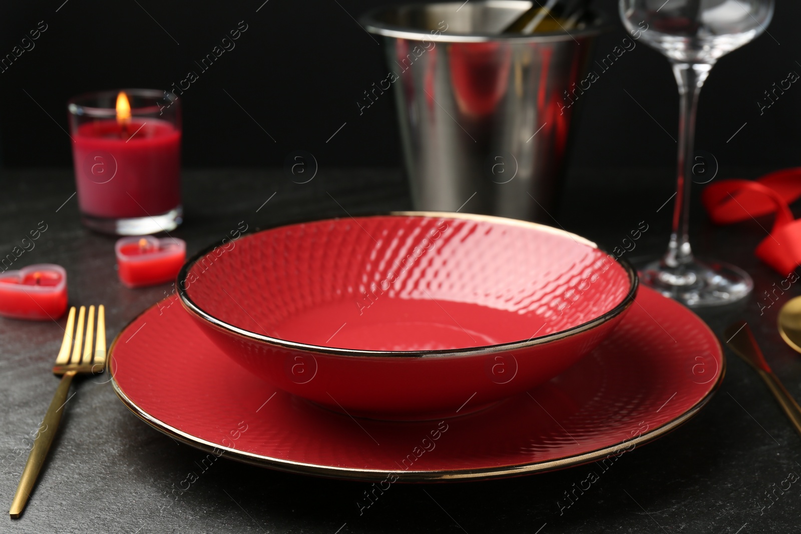 Photo of Place setting with heart shaped candles on dark gray table, closeup. Romantic dinner