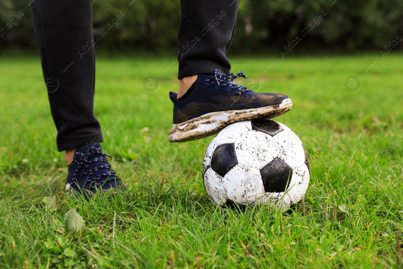 Photo of Man with dirty soccer ball on green grass outdoors, closeup