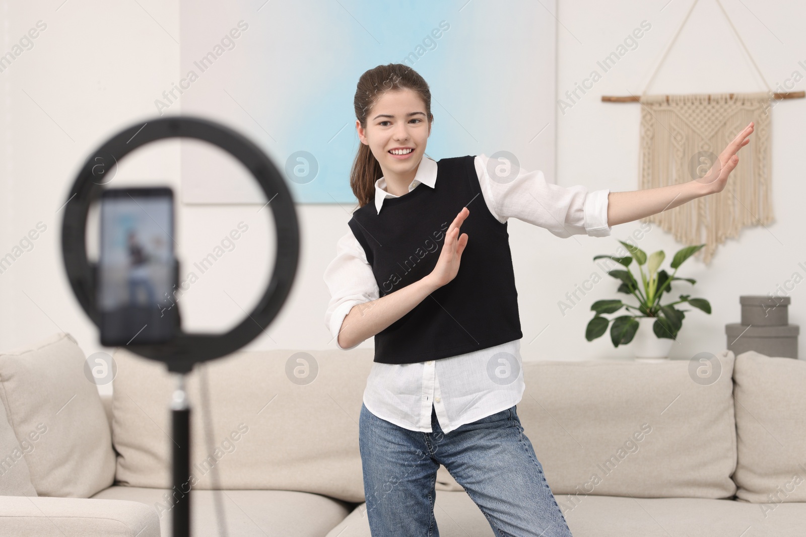 Photo of Smiling teenage blogger dancing while streaming at home