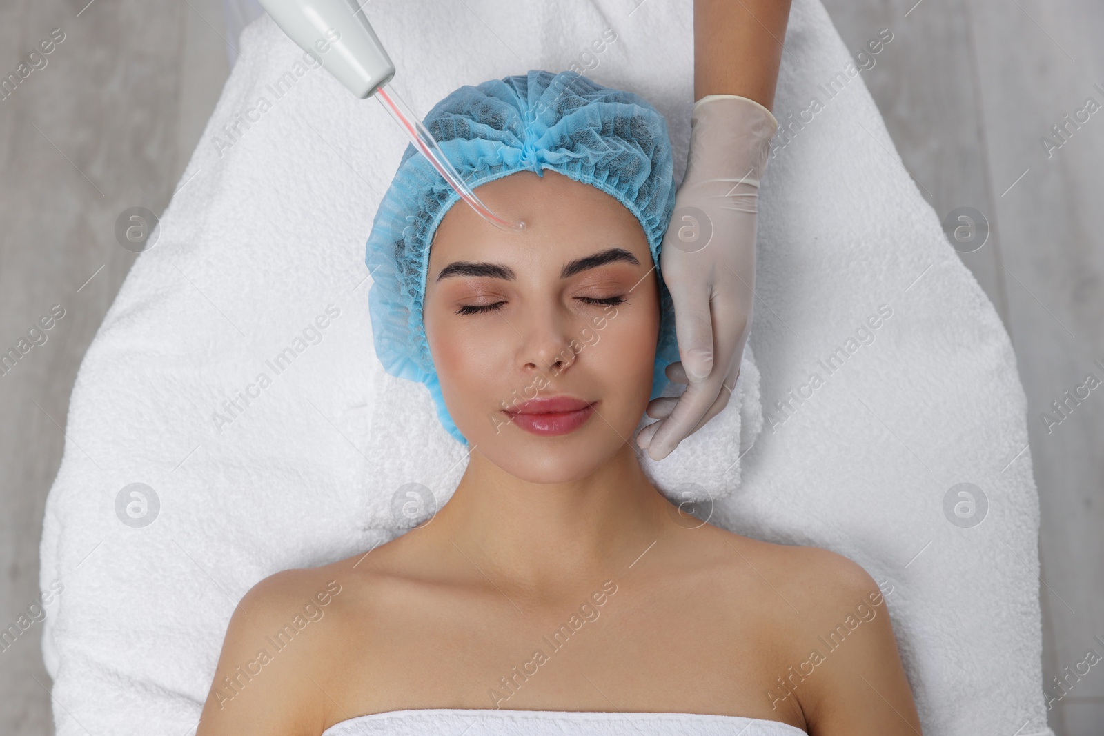 Photo of Young woman undergoing face rejuvenation procedure with darsonval in salon, top view