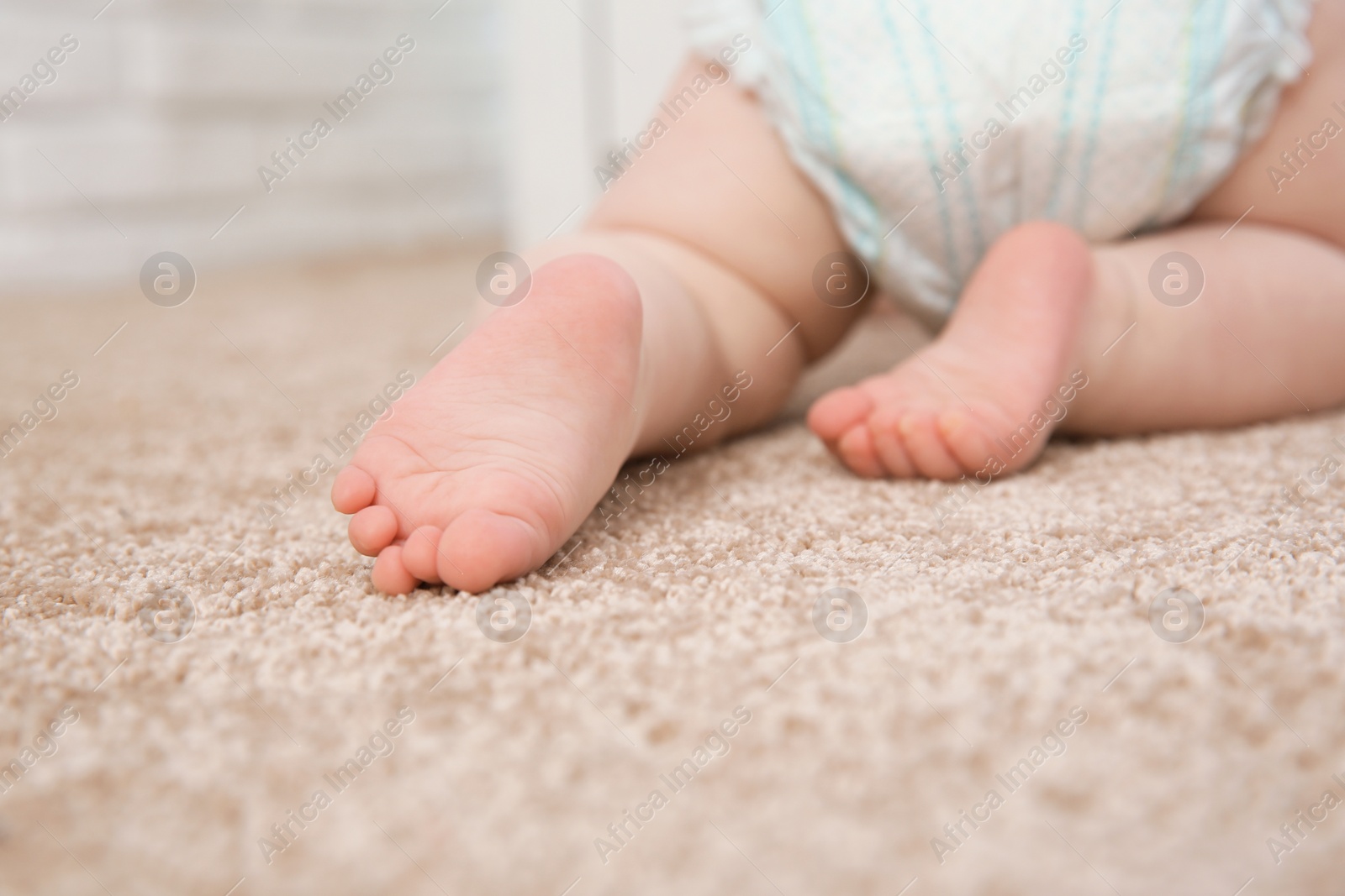 Photo of Cute little baby crawling on carpet indoors, closeup