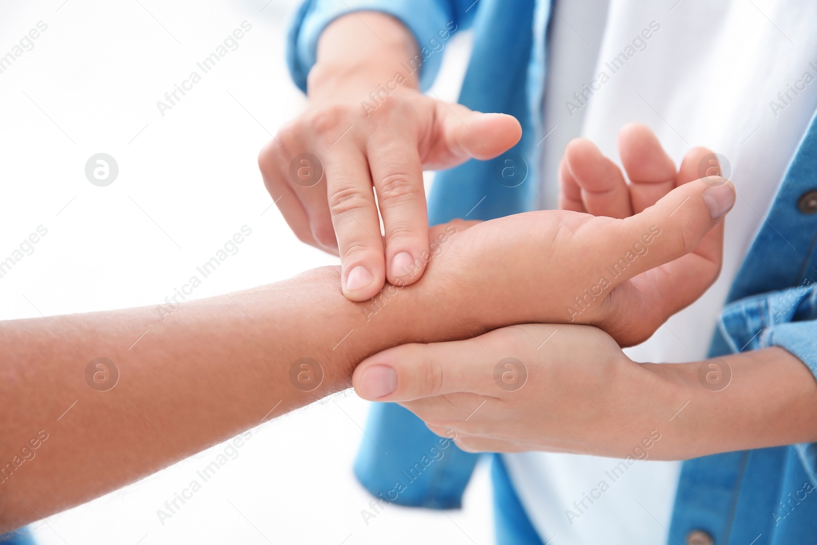 Photo of Young woman checking senior man's pulse on light background