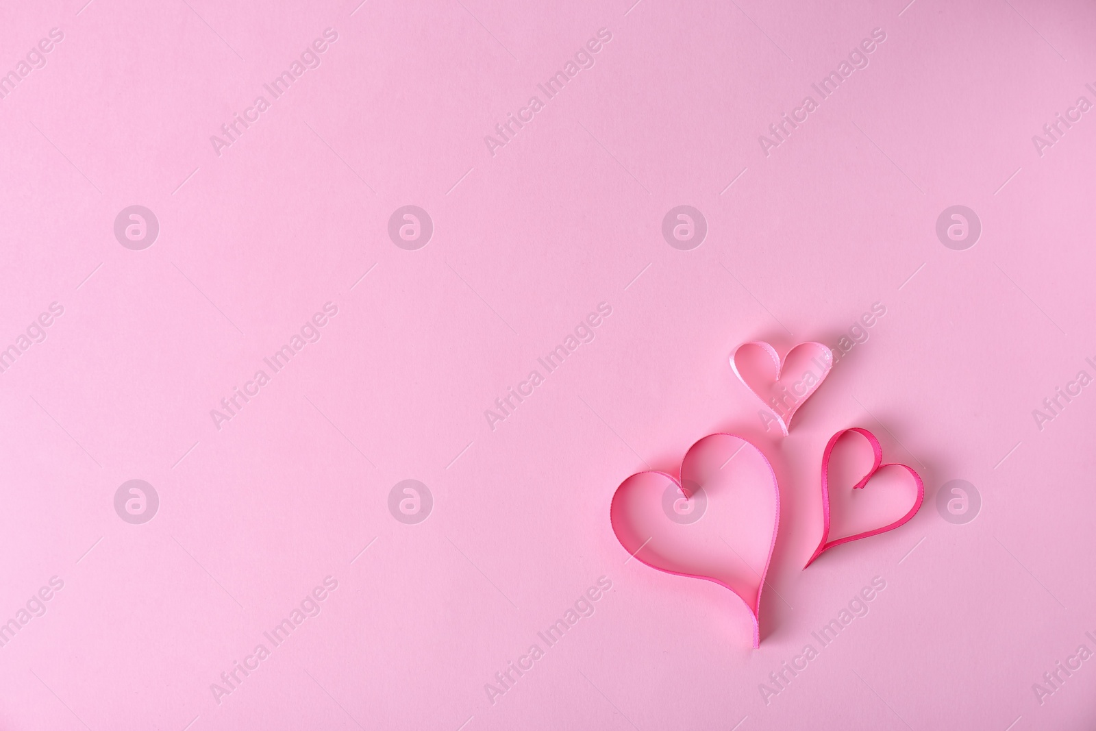 Photo of Hearts made of ribbons and space for text on color background, top view